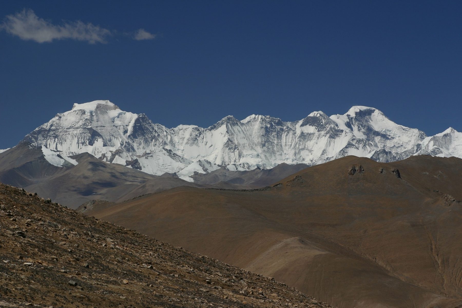 Snow-covered peaks of the Himalaya above a dry brown ridge